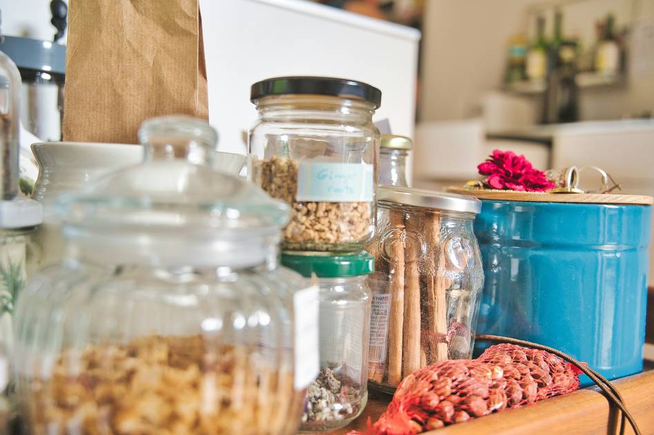 Close-up of reusable cups with lids on a wooden kitchen counter surrounded by plants