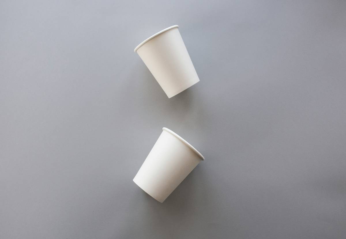 sustainable living reusable cup lid are shown in kitchen setting with bamboo utensils and compost bin